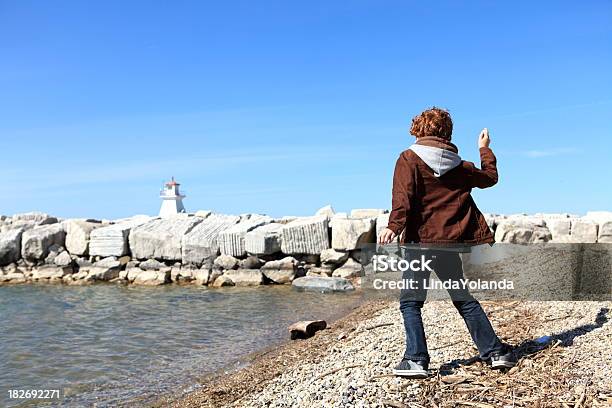 Boy Throwing Rocks By Lake Stock Photo - Download Image Now - Child, Rock - Object, Sea