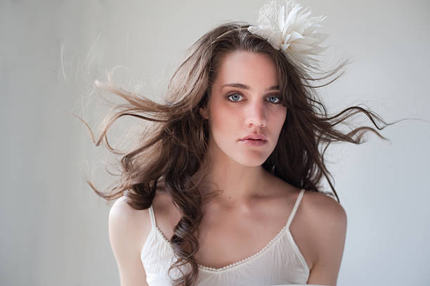 headshot of blowing hair woman with flower headpiece stock photo