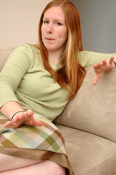 CasualWoman4 Red haired woman sitting on a couch. Expression says hold on paula jean myers stock pictures, royalty-free photos & images