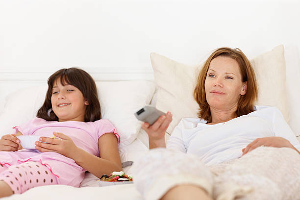 istock Mother with her daughter lying on bed and watching television 182694593