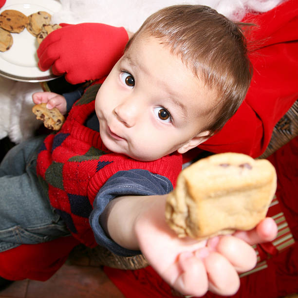 Toddler Holding Out Cookie From Santa's Plate.