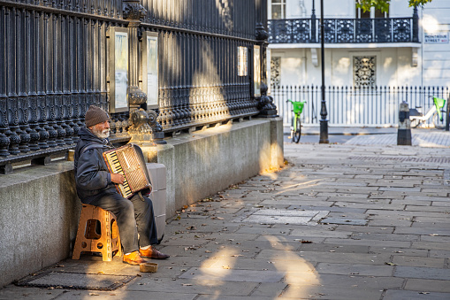 Museum Street, London, England - October 25th 2023: Old man playing accordion outside British Museum in the afternoon sun