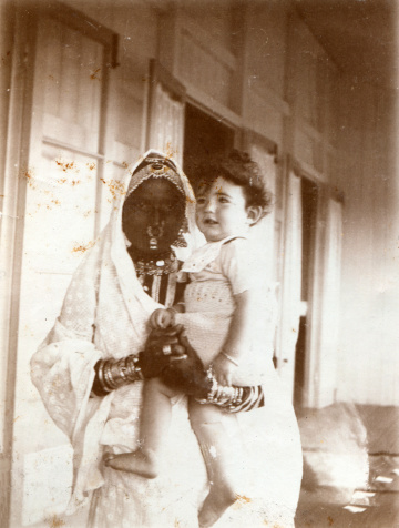 Vintage photograph of a young english girl in the arms of her native nanny / nurse.   Circa 1900 - 1910