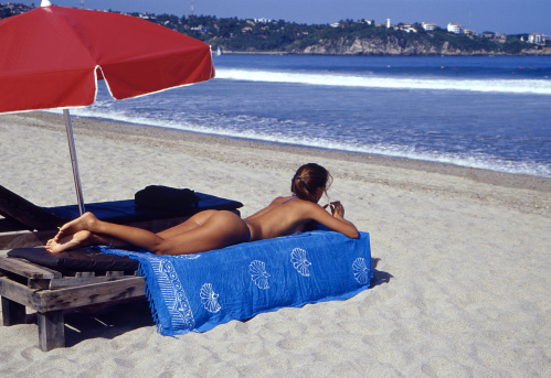 a young woman lies in the sun on the beach