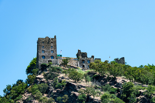 View from the river Rhine at the East bank with the ruins of the Liebenstein castle on the top of a hill near the village of Kamp-Bornhofen.