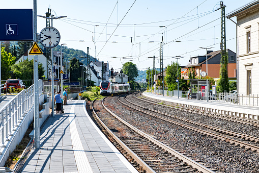 People waiting for the train from Mittelrhein Bahn to Koblenz on the platform of Kamp-Bornhofen railway station on the east bank of the river Rhein.