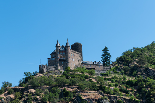 View from the river Rhine at the East bank with the medieval castle Katz (Cat) from 1393 on the top of a hill overlooking the village of Sankt Goarshausen.