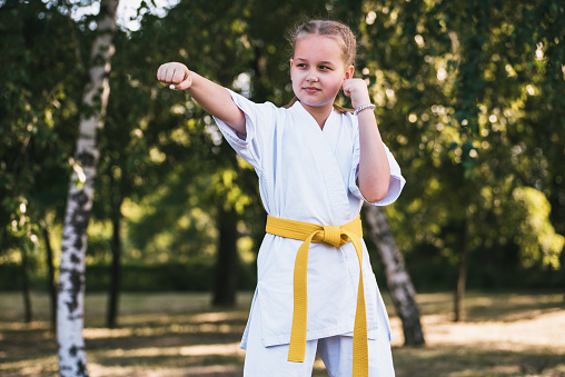 Karateka girl making a hand strike at summer park outdoors. The concept of martial arts - karate, kung fu, taekwondo.