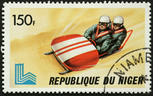 old fashioned bobsled racers on a postage stamp