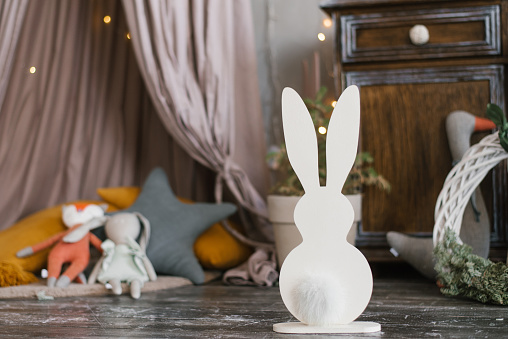 Christmas decor for the children's room: homemade plywood bunnies with soft tails on the background of children's toys. Copy space