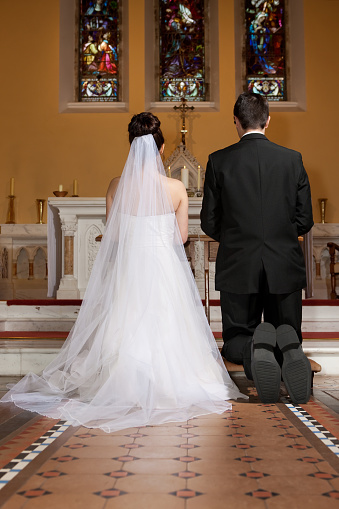 bride and groom in the church kneeling,, waiting for the priest