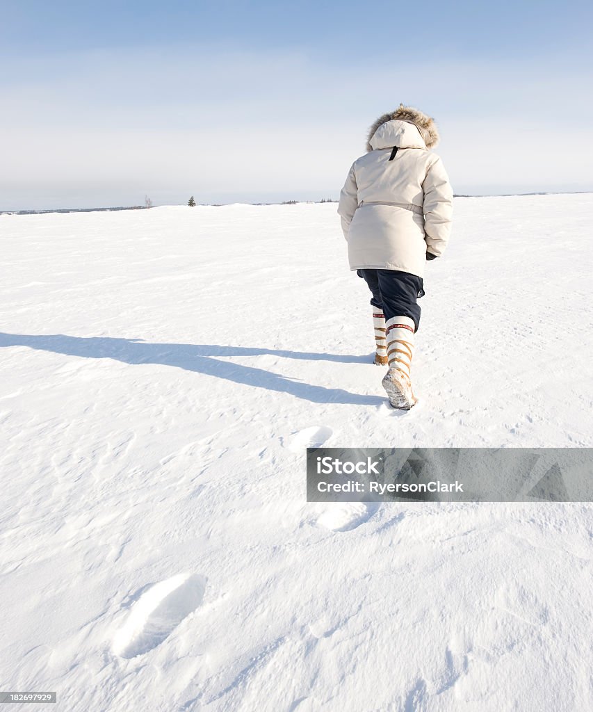 Woman walks the Arctic, Yellowknife. A woman wearing traditional style mukluks (winter boots) strides across the surface of Great Slave Lake in winter.  Click to view similar images. Canada Stock Photo