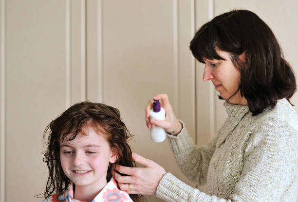 mother spraying child's wet hair with product stock photo