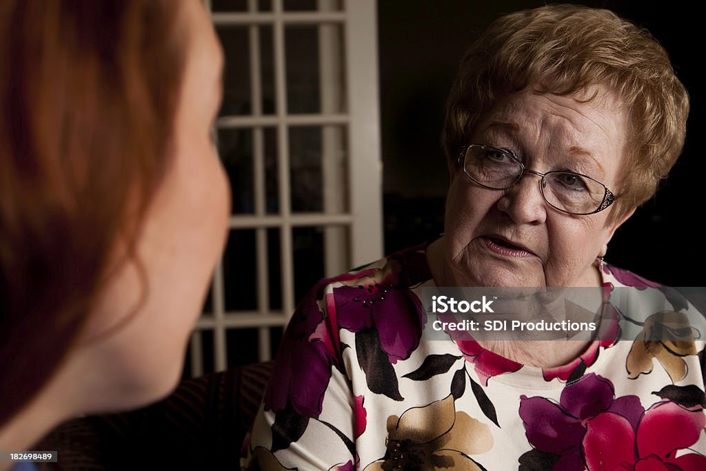 Preoccupato Senior Adulti con grave conversazione con giovane donna - Foto stock royalty-free di Donne giovani