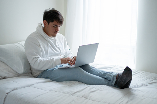 Un hombre usando su ordenador en la cama