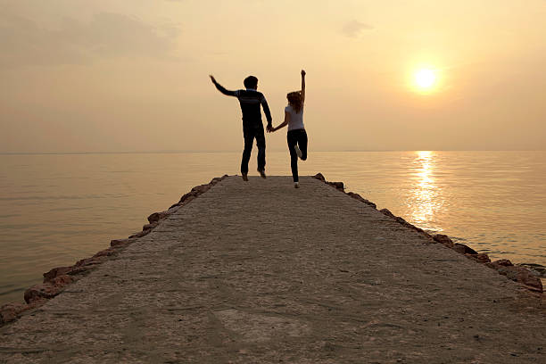 istock Happy couple jumping at sunset on a jetty 182699969