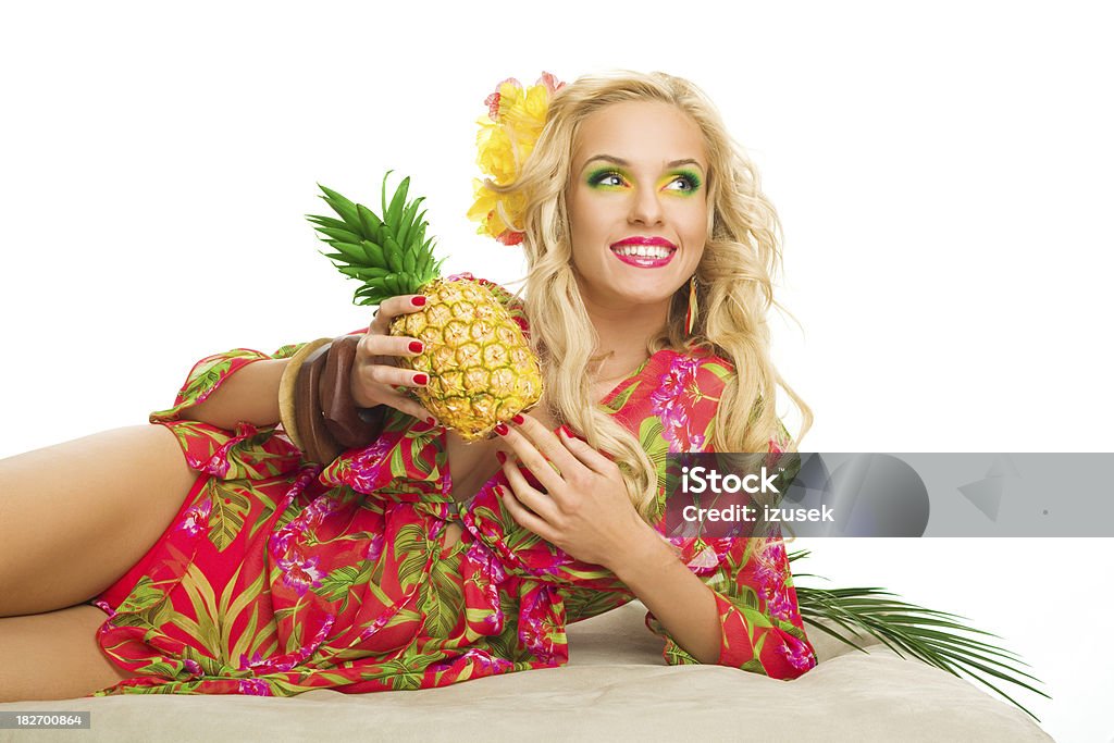 Summer portrait of attractive blonde woman holding pineapple fruit "Summer portrait of a smiling beautiful blonde woman laying down, wearing a colorful tunic and holding a pineapple fruit." 20-24 Years Stock Photo