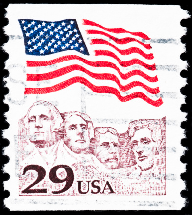 Royalty free stock photo of US postage stamp. It represents the American flag waving  above Mt. Rushmore featured on a 29-cent stamp.