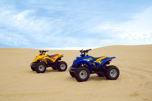 Two four wheel buggies from the side in the sand dunes