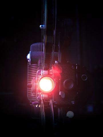 Detail of an old-fashioned 16mm film movie projector with the light on