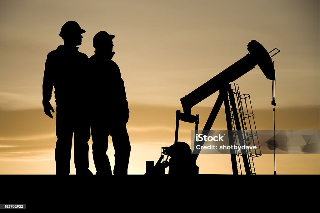 Icons of the Oil Industry Two industry workers stand next to an iconic symbol of the oil and gas industry - an oil pumpjack. Drilling Rig Stock Photo