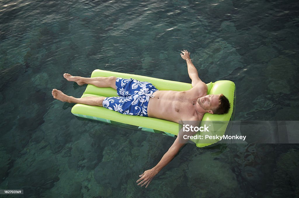 Ragazzo galleggia su Lilo in verde smeraldo e acque - Foto stock royalty-free di A petto nudo