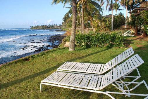 Two beach chairs at the water front property in Maui overlooking Pacific ocean. Pa'ia town area.