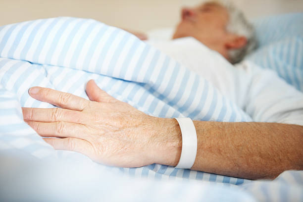 istock Man lying in hospital bed with a band on hand 182703564
