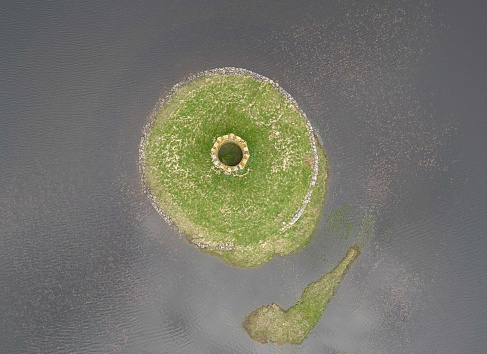 Aerial overhead drone view of Scolpaig Tower, a Georgian folly on the Outer Hebridean island of North Uist on the northwest coast of Scotland. Built around 1830 in the middle of Loch Scolpaig. The abandoned monument stands on an exposed area of North Atlantic coastline.