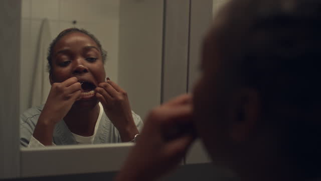 African American Female Nurse Flossing Teeth before Work