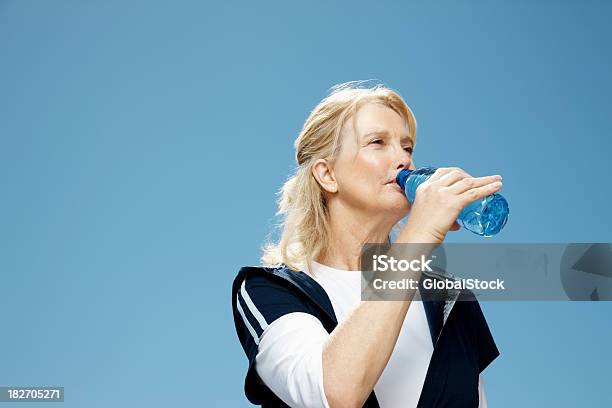 Mujer Madura Agua Potable Contra El Cielo Despejado Foto de stock y más banco de imágenes de 50-54 años