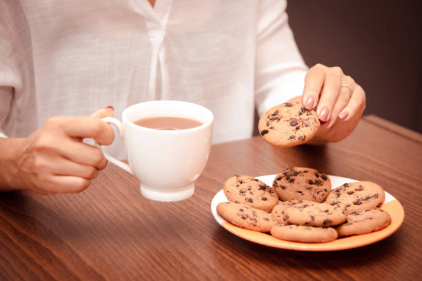 istock Woman eats cookie with chocolate chip and tea in break of work in home office 1827056331