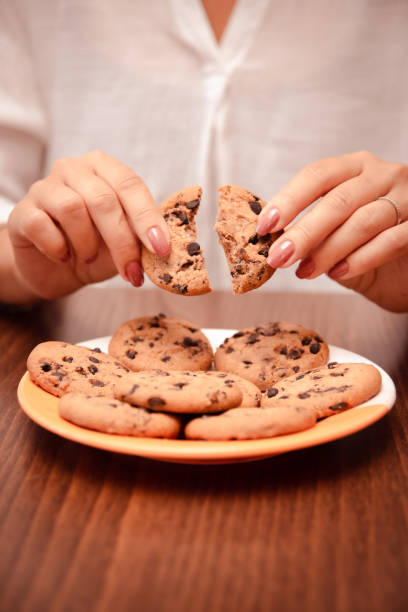 istock woman hands breaks crisp cookie with chocolate chip in half 1827056333