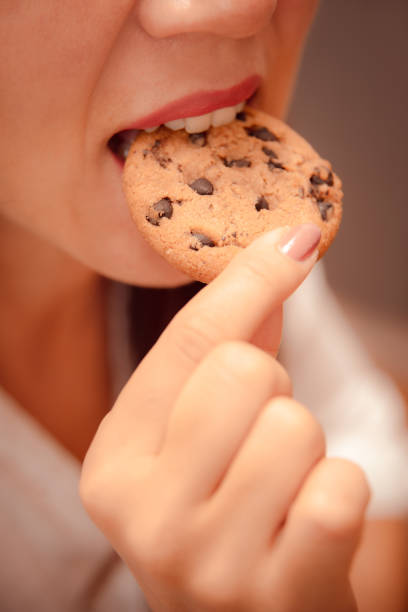 closeup mouth eat cookie. hungry woman quenches hunger with sweets