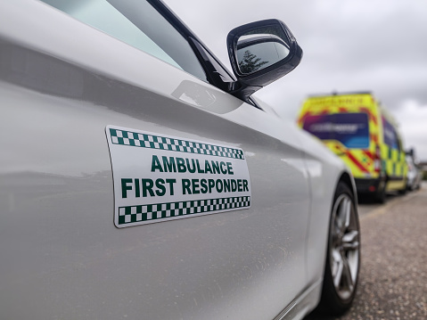 Ambulance first responder attending a medical emergency. UK volunteer community first responder car with an ambulance in the background