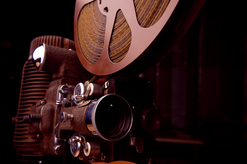 An old 16mm movie projector with a loaded reel of film.