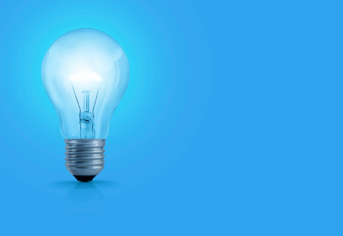 A light bulb with glowing filament on blue background.