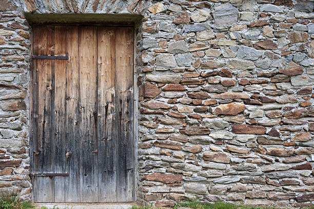 Old stone wall of a historical farm house with wooden door.