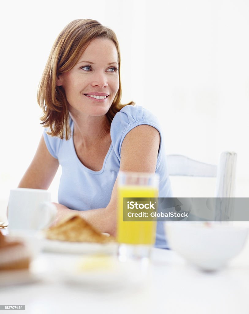 Smiling mid adult woman sitting at her breakfast table Pretty mid adult woman sitting at her breakfast table 30-34 Years Stock Photo