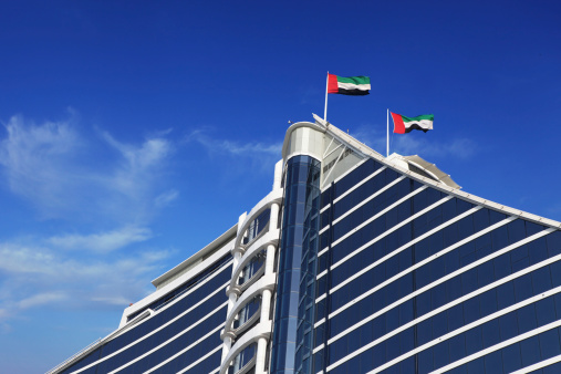 uae flags waving on top of a modern styled hotel in dubai - uae..other tower and construction in Dubai & UAE Images..