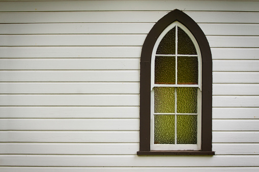 A single church window in an historic pioneer church, offset with plenty of copy space.