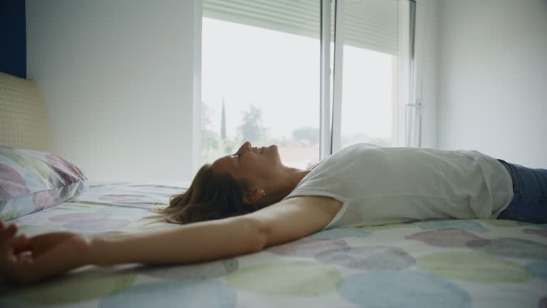 SLO MO Cheerful woman falling with arms outstretched on bed at home