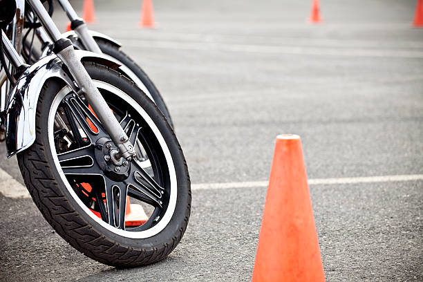 Close-up of a motorcycle wheel near an orange cone Motorcycle training. Shot with 5DII, short depth of field. road warning sign photos stock pictures, royalty-free photos & images