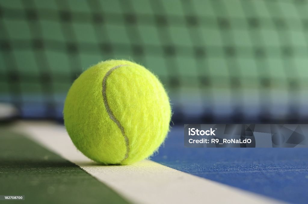 Tennis ball on the line with net in background Tennis ball on the line with net in background in indoor tennis court Tennis Stock Photo