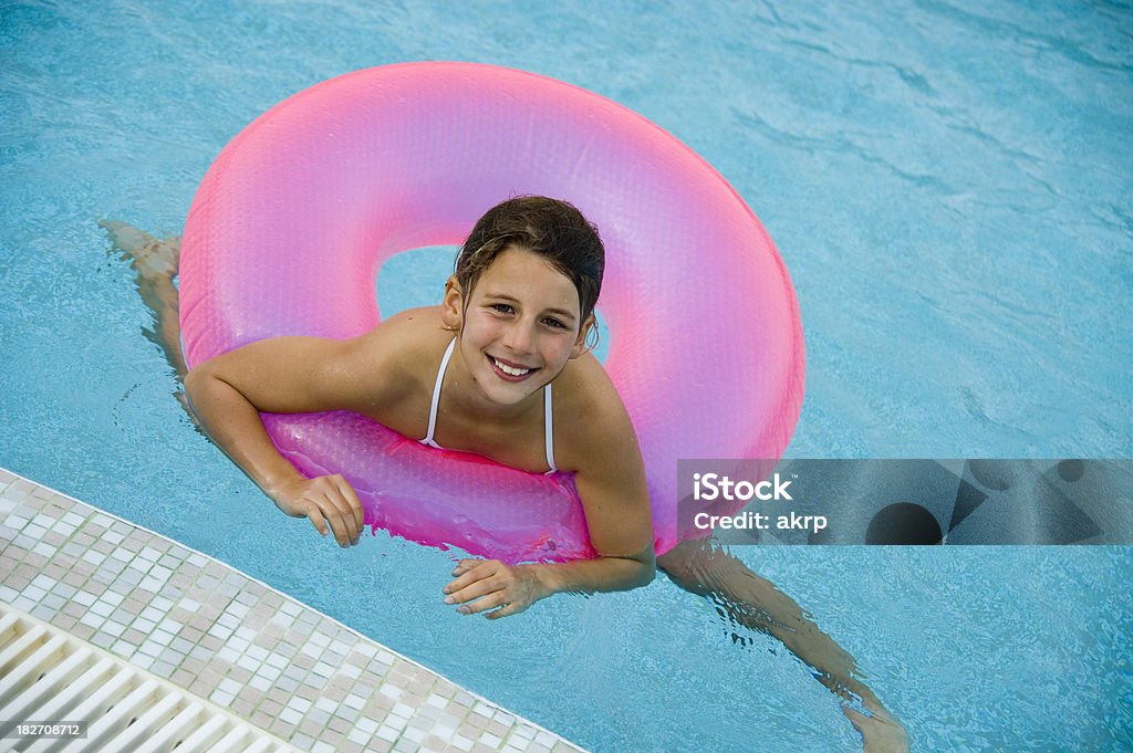 Girl floating in pink swimming tube Pretty pre teen girl with wet hair floating in a pink swimming tube on the water. 8-9 Years Stock Photo