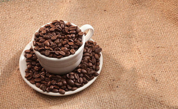 Tasse Kaffee und Bohnen auf Sackleinen. – Foto