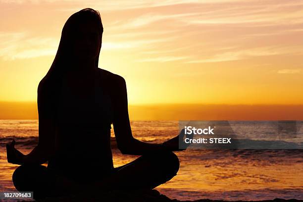 Silhouetted Donna Nella Posizione Del Loto In Mare Al Tramonto - Fotografie stock e altre immagini di Acqua