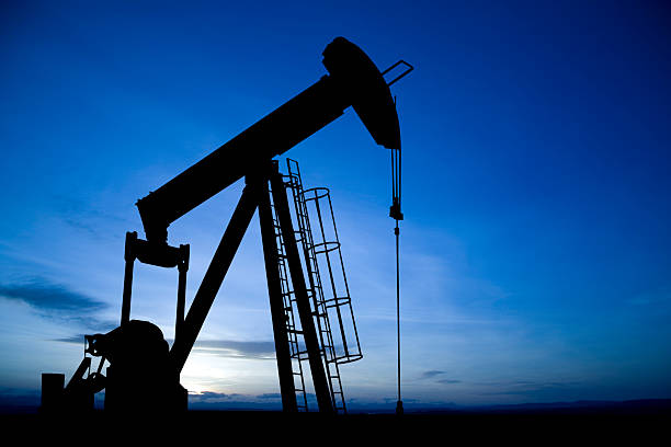 Pumpjack on Blue An iconic oil and gas industry symbol taken at dusk. wellhead stock pictures, royalty-free photos & images