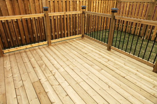 Wood deck with railing and wooden fence in the background.