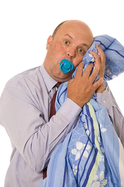 A business man sucking on dummy while hugging blanket.